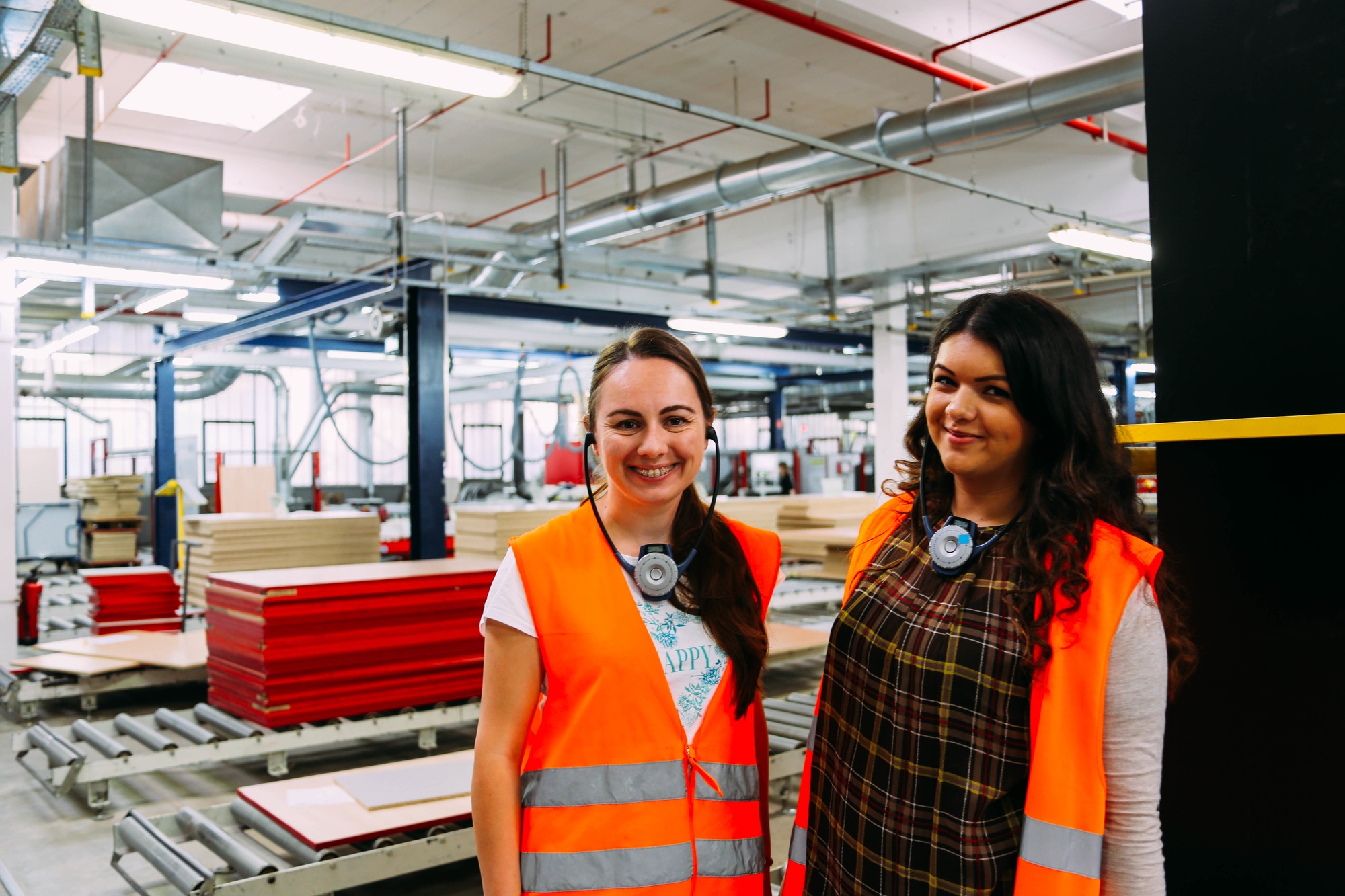 Happy Latino women in a manufacturing factory wearing Personal Protective Equipment (PPE)